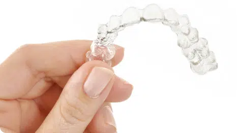 Hand som håller i en invisalign tandställning